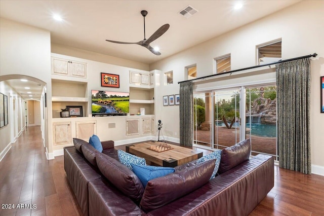 living room featuring ceiling fan, built in features, and dark wood-type flooring