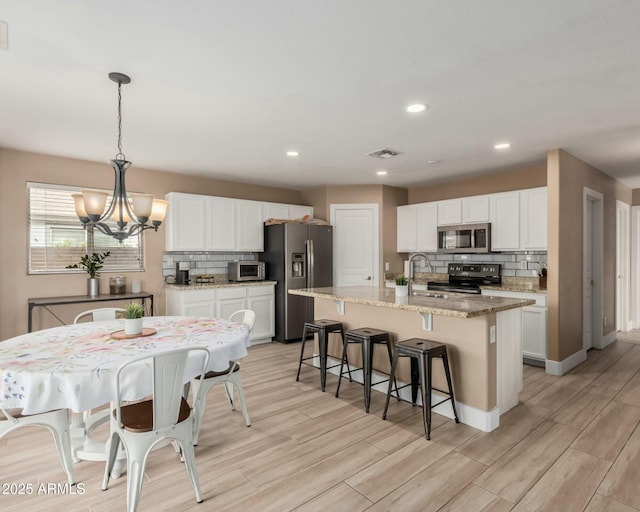22337 E Via Del Palo, Queen Creek, AZ 85142 - kitchen with white cabinetry, a kitchen bar, a chandelier, visible vents, and appliances with stainless steel finishes