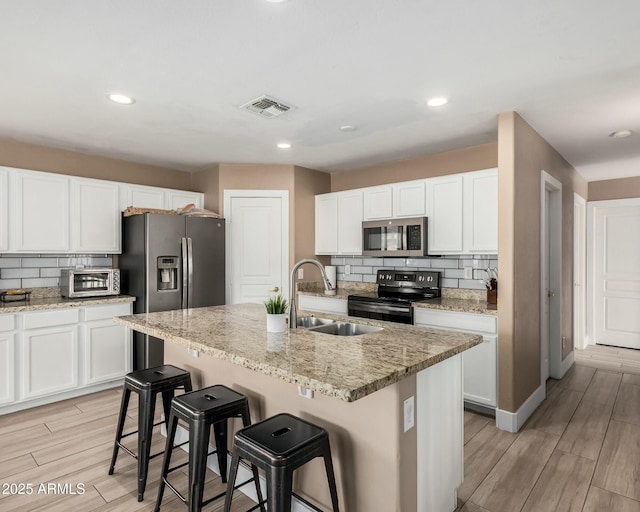 22337 E Via Del Palo, Queen Creek, AZ 85142 - kitchen with a kitchen island with sink, wood finish floors, appliances with stainless steel finishes, a sink, and a breakfast bar area