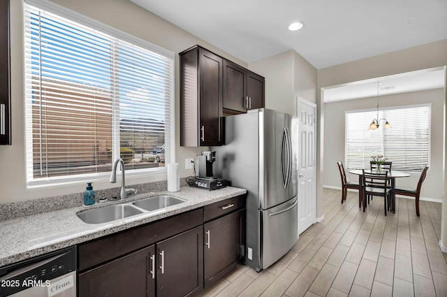 kitchen with light wood-style flooring, dark brown cabinetry, a sink, freestanding refrigerator, and dishwasher