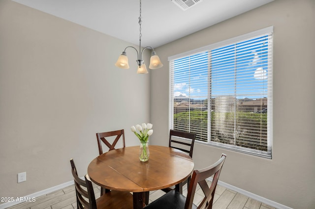 dining space with a chandelier, light wood-type flooring, visible vents, and baseboards