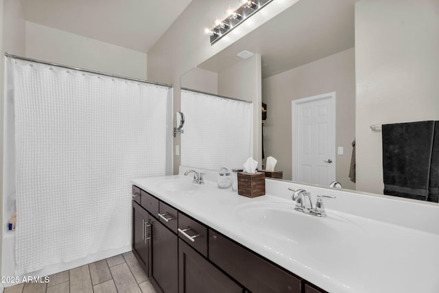 full bathroom with double vanity, wood tiled floor, and a sink