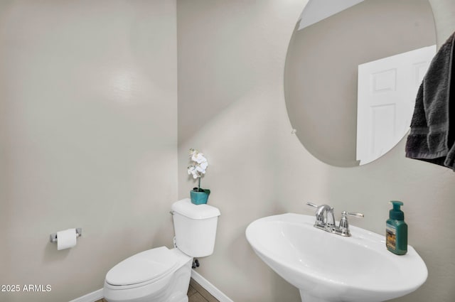 bathroom with baseboards, a sink, and toilet