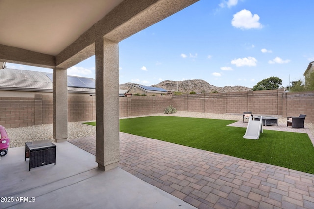 view of patio / terrace with a fire pit, a fenced backyard, and a mountain view