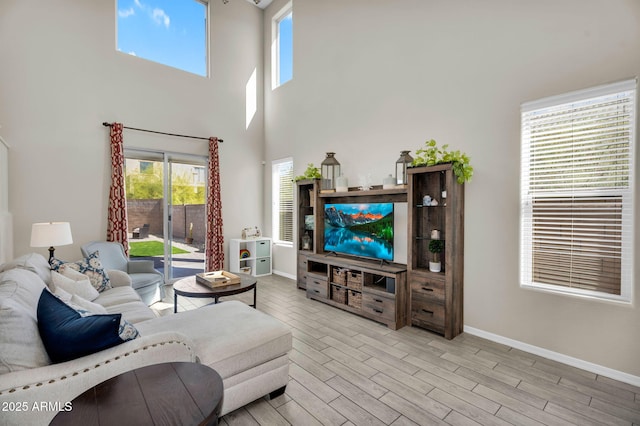 living room with a towering ceiling, baseboards, and wood finished floors