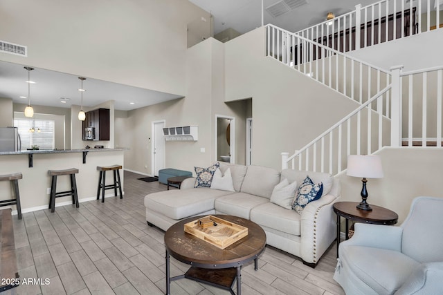 living room with stairs, wood finish floors, visible vents, and baseboards