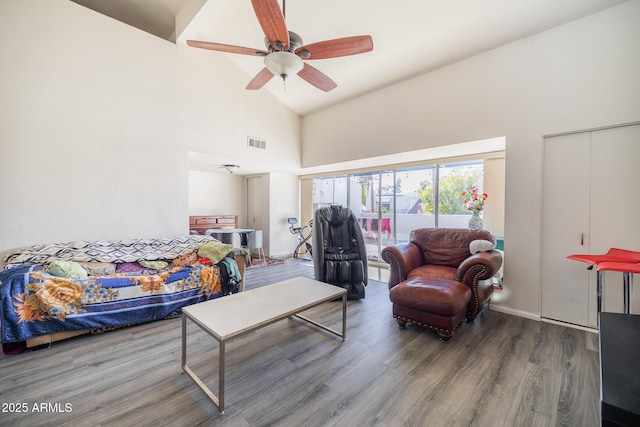 living room with hardwood / wood-style flooring, ceiling fan, and high vaulted ceiling