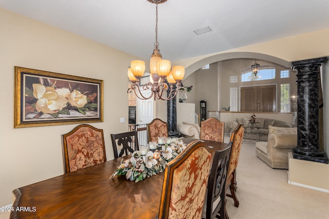 dining space featuring decorative columns, an inviting chandelier, and light carpet