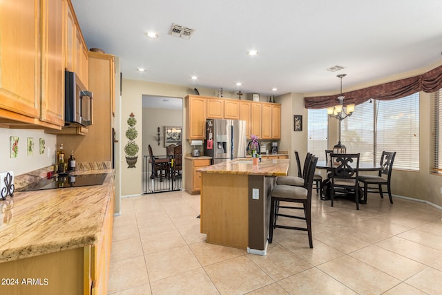 kitchen with a kitchen breakfast bar, decorative light fixtures, an inviting chandelier, appliances with stainless steel finishes, and a kitchen island with sink