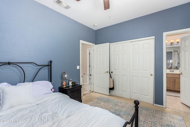 bedroom with light tile patterned floors, ensuite bath, sink, ceiling fan, and a closet