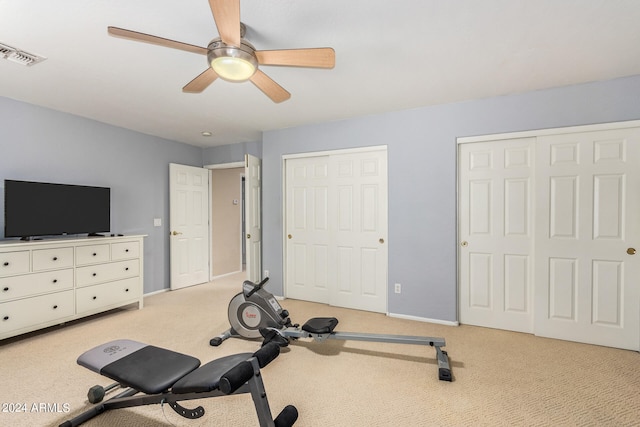 exercise area with ceiling fan and light colored carpet