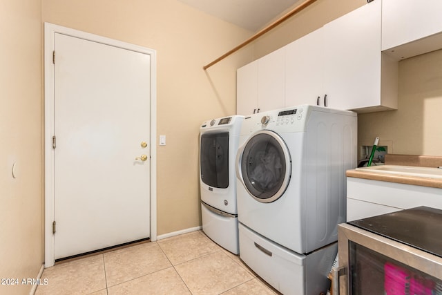 clothes washing area with light tile patterned flooring, cabinets, and washer and dryer