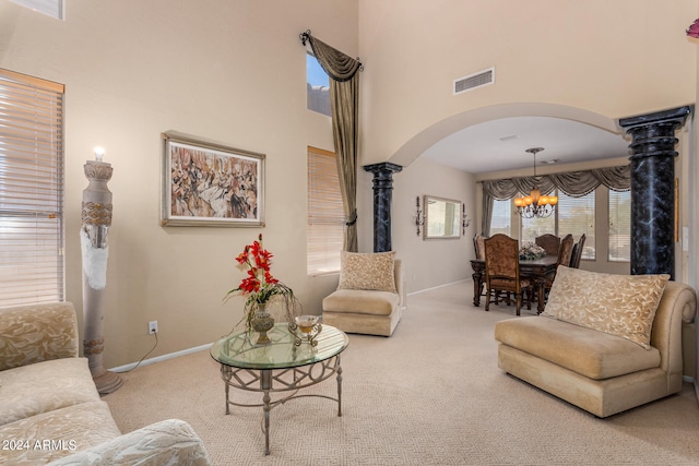 carpeted living room featuring decorative columns and an inviting chandelier