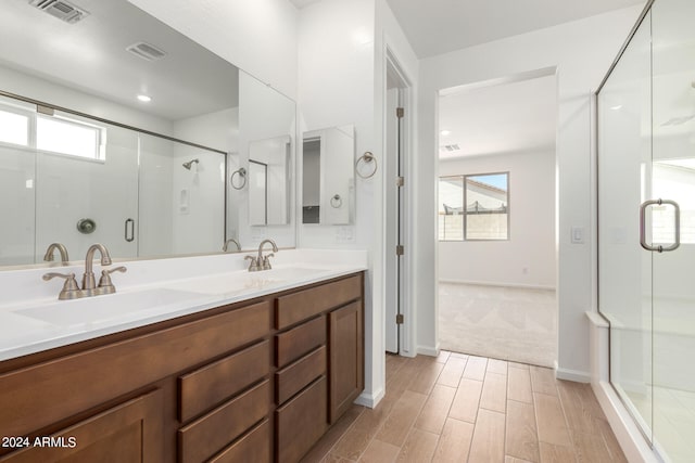 bathroom with vanity, hardwood / wood-style floors, plenty of natural light, and a shower with shower door