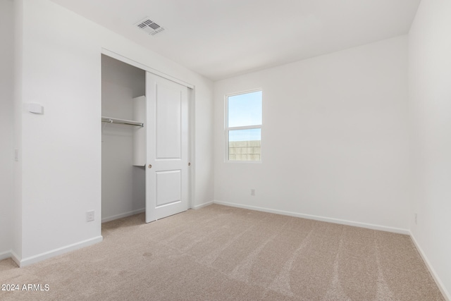 unfurnished bedroom featuring light carpet and a closet