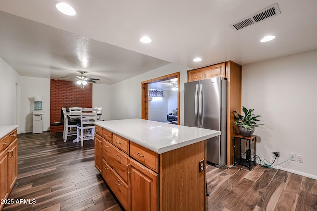 kitchen featuring dark wood-type flooring, ceiling fan, stainless steel fridge, and a center island