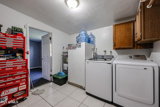 laundry area with cabinets, a textured ceiling, light tile patterned floors, washing machine and dryer, and water heater