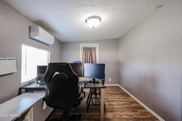 office featuring dark wood-type flooring, a wall unit AC, and a textured ceiling