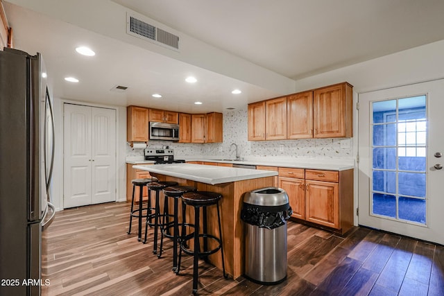 kitchen featuring stainless steel appliances, a kitchen island, sink, and dark hardwood / wood-style floors