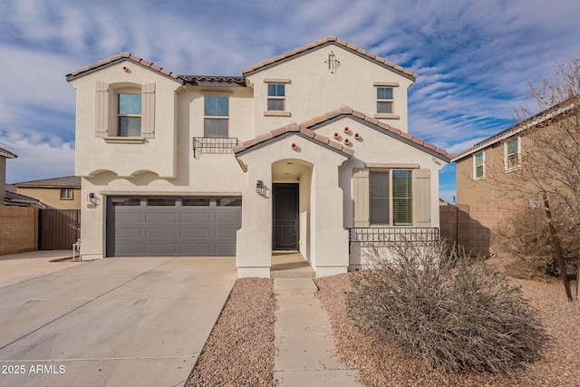 mediterranean / spanish-style home with a garage, fence, concrete driveway, and stucco siding