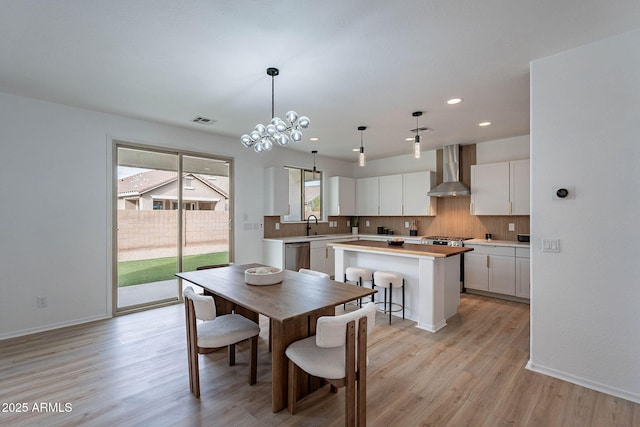 dining space featuring light wood-style floors, baseboards, and visible vents