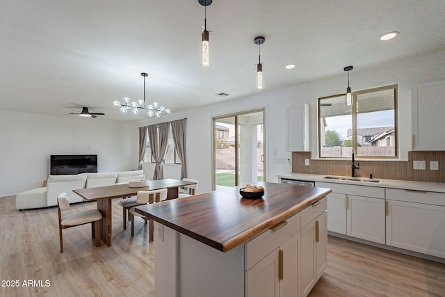 kitchen with open floor plan, white cabinets, a sink, wood counters, and light wood-type flooring