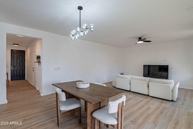 dining room featuring light wood-style flooring, baseboards, and ceiling fan with notable chandelier