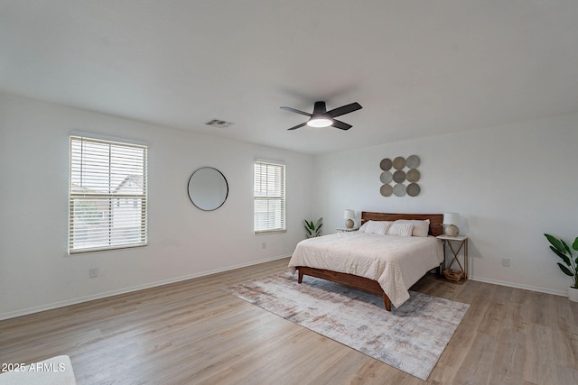 bedroom featuring a ceiling fan, visible vents, light wood-style flooring, and baseboards