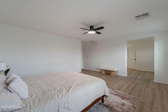 bedroom featuring light wood-style floors, baseboards, visible vents, and a ceiling fan