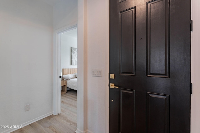 hallway featuring light wood-style flooring and baseboards