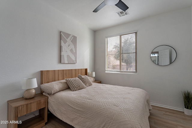 bedroom featuring a ceiling fan, baseboards, visible vents, and wood finished floors