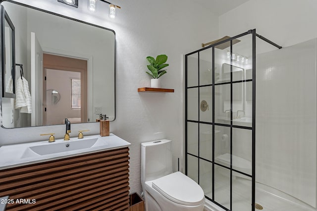 full bathroom with a tile shower, vanity, and toilet