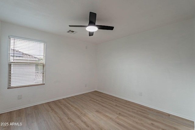 spare room featuring light wood-style floors, visible vents, ceiling fan, and baseboards