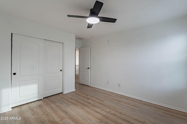 unfurnished bedroom featuring baseboards, visible vents, light wood-style flooring, ceiling fan, and a closet