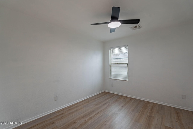 empty room featuring ceiling fan, light wood-style flooring, visible vents, and baseboards