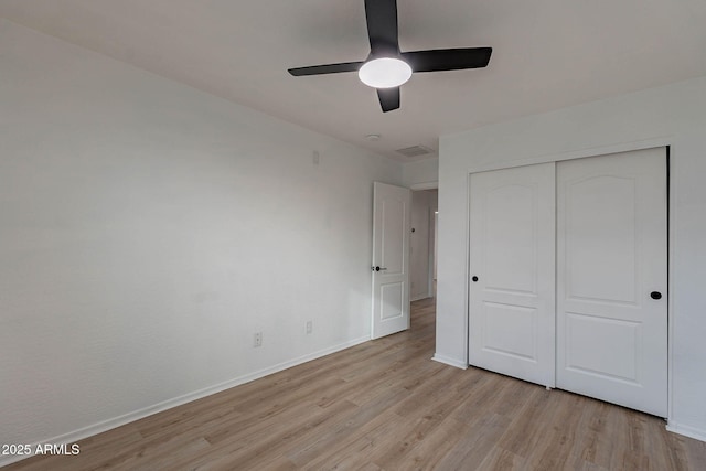 unfurnished bedroom with light wood finished floors, baseboards, visible vents, ceiling fan, and a closet