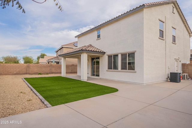 rear view of property with a tiled roof, a patio area, a fenced backyard, and stucco siding