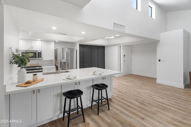 2935 N 68th St Unit 205, Scottsdale, AZ 85251 - kitchen with stainless steel appliances, a peninsula, a breakfast bar area, light countertops, and white cabinetry