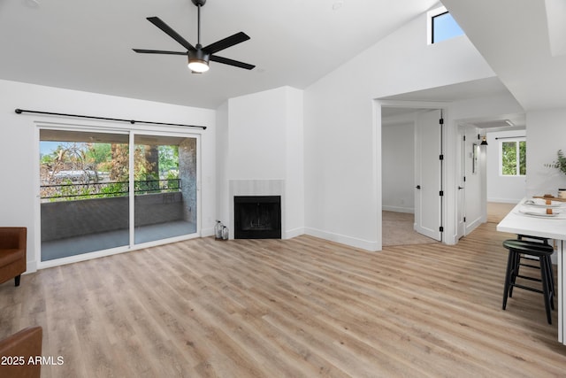 2935 N 68th St Unit 205, Scottsdale, AZ 85251 - unfurnished living room featuring light wood finished floors, ceiling fan, a fireplace, and high vaulted ceiling