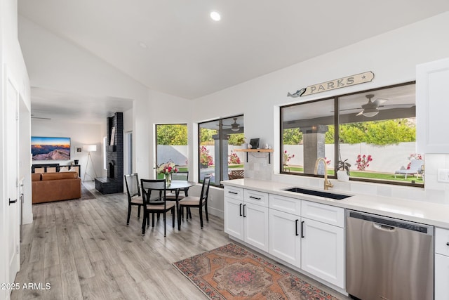 kitchen featuring lofted ceiling, sink, light wood-type flooring, white cabinetry, and stainless steel dishwasher