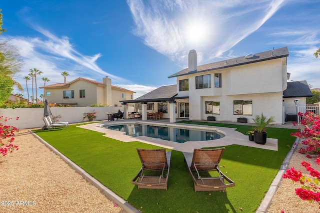 rear view of house with a lawn, a fenced in pool, and a patio area