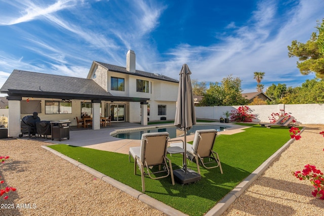 back of property with a yard, a patio, and a fenced in pool