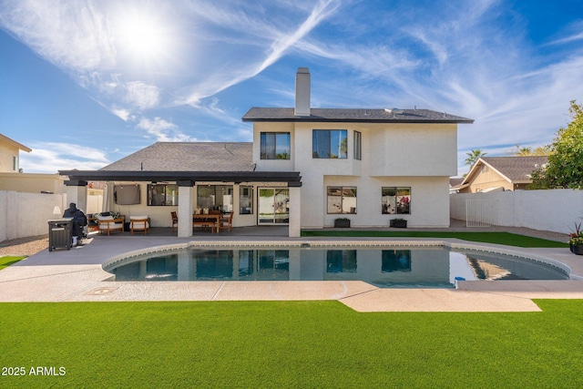 rear view of house with a patio, outdoor lounge area, a fenced in pool, and a lawn