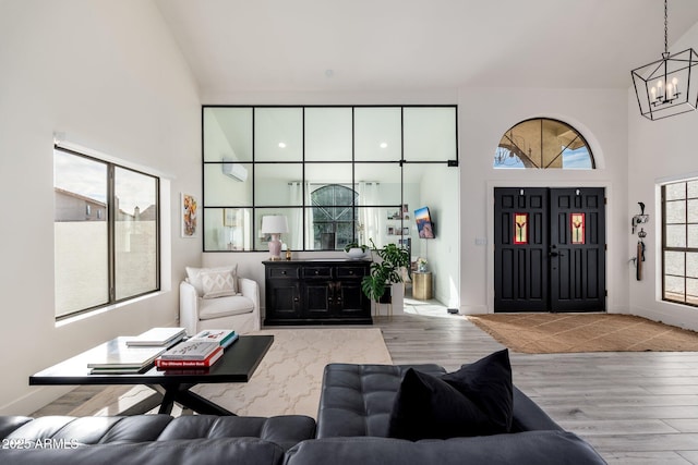 living room with light hardwood / wood-style floors, a chandelier, and a towering ceiling