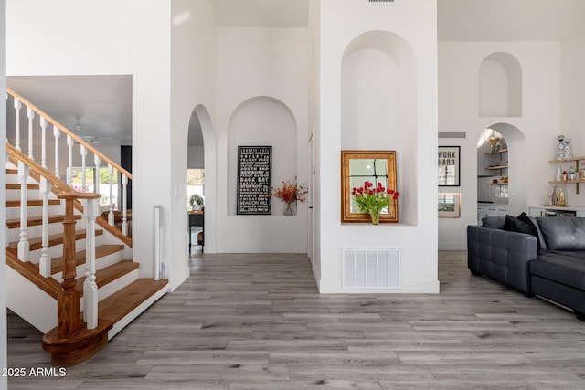 entryway with a high ceiling, bar area, and light wood-type flooring