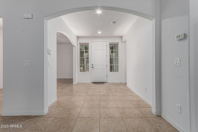 entryway featuring recessed lighting, visible vents, arched walkways, light tile patterned flooring, and baseboards