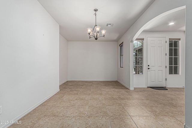 tiled entryway with arched walkways, a notable chandelier, visible vents, and baseboards