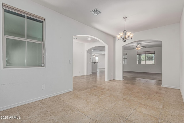 unfurnished room featuring ceiling fan with notable chandelier, baseboards, visible vents, and arched walkways
