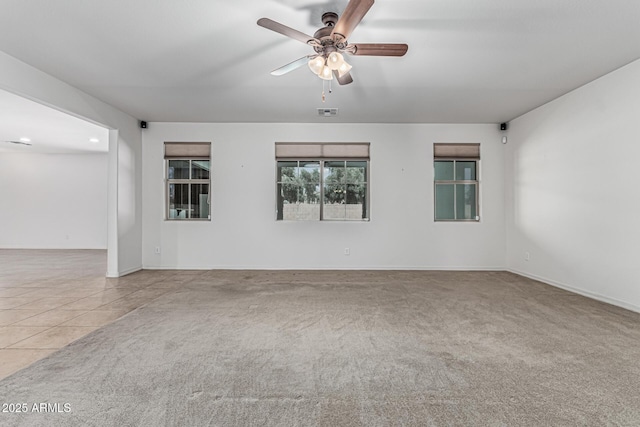 empty room with carpet floors, visible vents, baseboards, and ceiling fan
