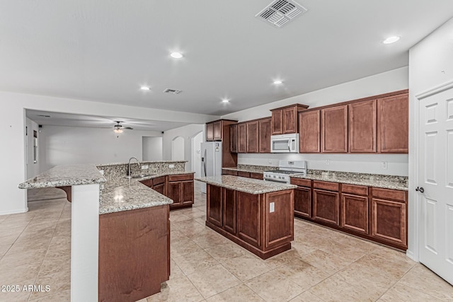 kitchen with a large island, visible vents, a sink, and white appliances